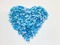 Heart-shaped pile of 6mm iridescent flower sequins in blue on a white background