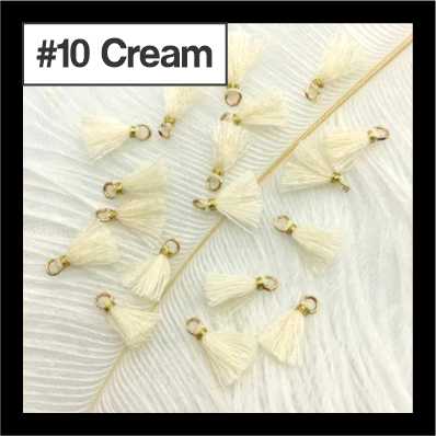 Scattered 1cm cream cotton tassels with gold-tone rings on white fur, labelled #10