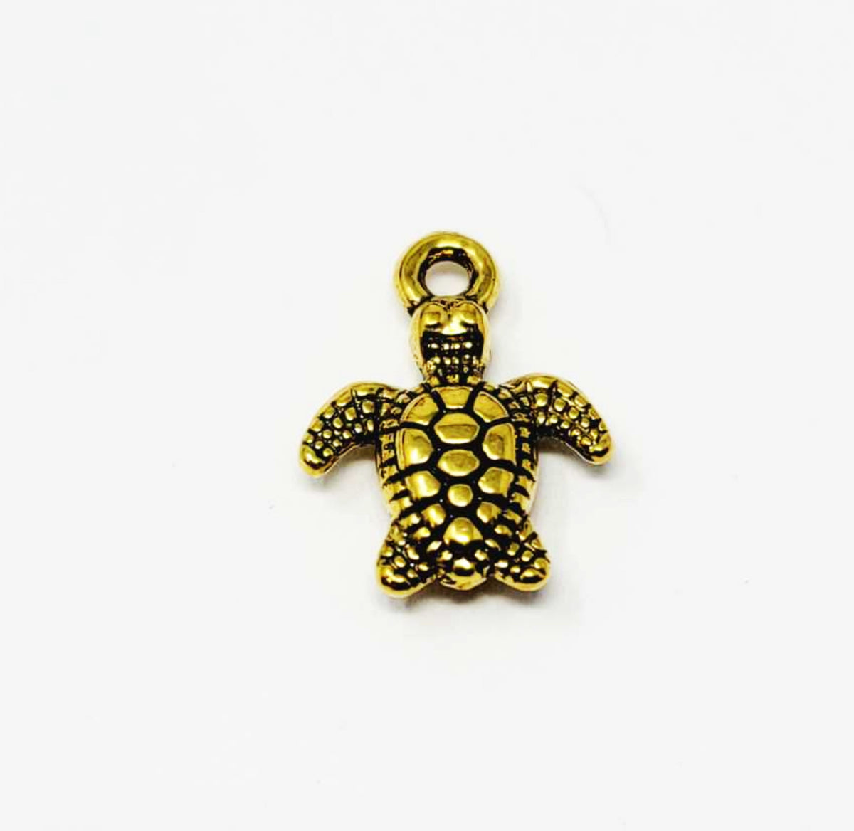 Close-up of a gold-tone 10 x 13mm turtle pendant with a dotted shell and top loop