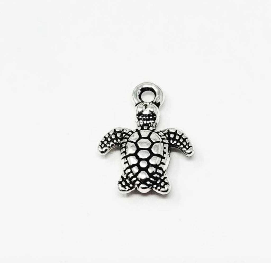 Close-up of a silver-tone 10 x 13mm turtle pendant with a dotted shell and top loop