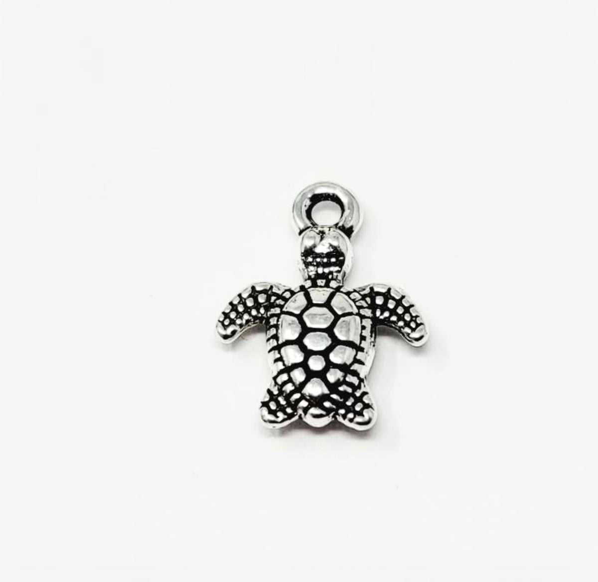 Close-up of a silver-tone 10 x 13mm turtle pendant with a dotted shell and top loop