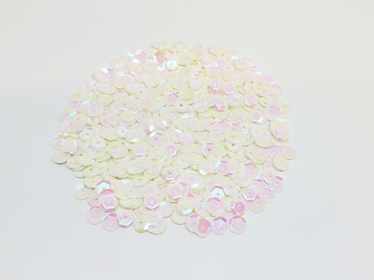 Pile of 6mm round buttercream sequins with centre holes, on a white background