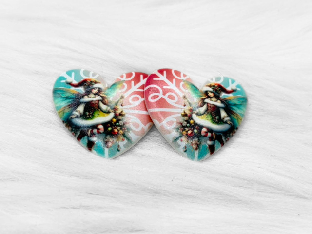 Pair of 37mm resin heart cabochons (cabs) with a Christmas fairy in a Santa hat on teal and red snowflake swirls