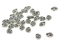 Silver-tone 11 x 16mm lotus flower spacer beads scattered on white