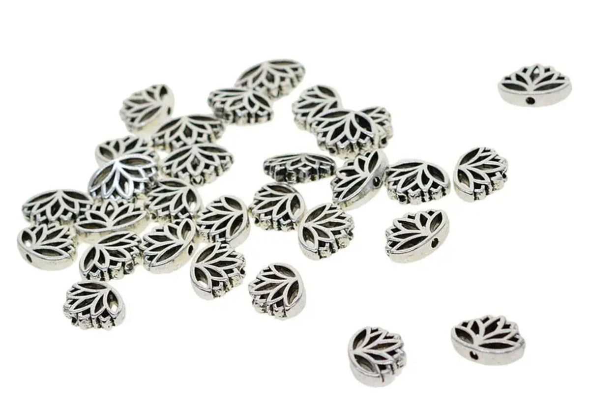 Silver-tone 11 x 16mm lotus flower spacer beads scattered on white