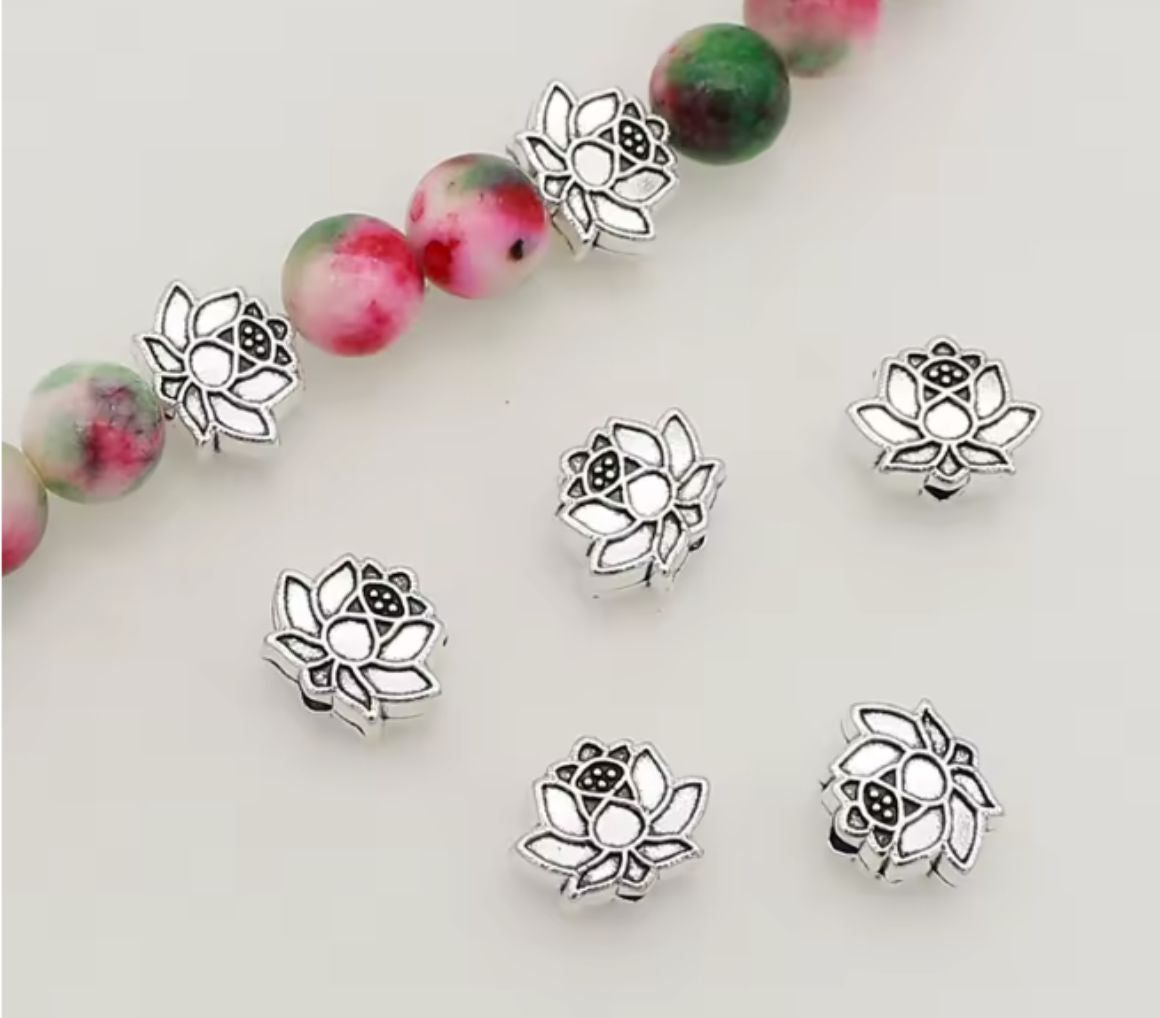 Silver-tone 12 x 9mm lotus flower spacer beads beside a strand of beads