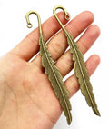 Bronze-tone 13 x 116mm metal feather bookmark held in a hand