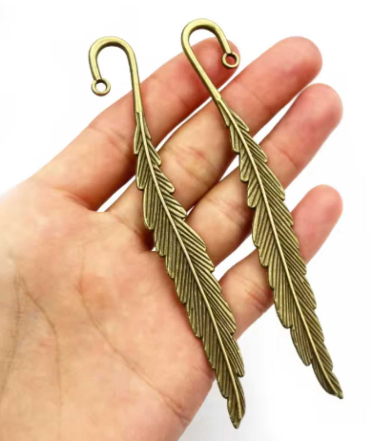 Bronze-tone 13 x 116mm metal feather bookmark held in a hand