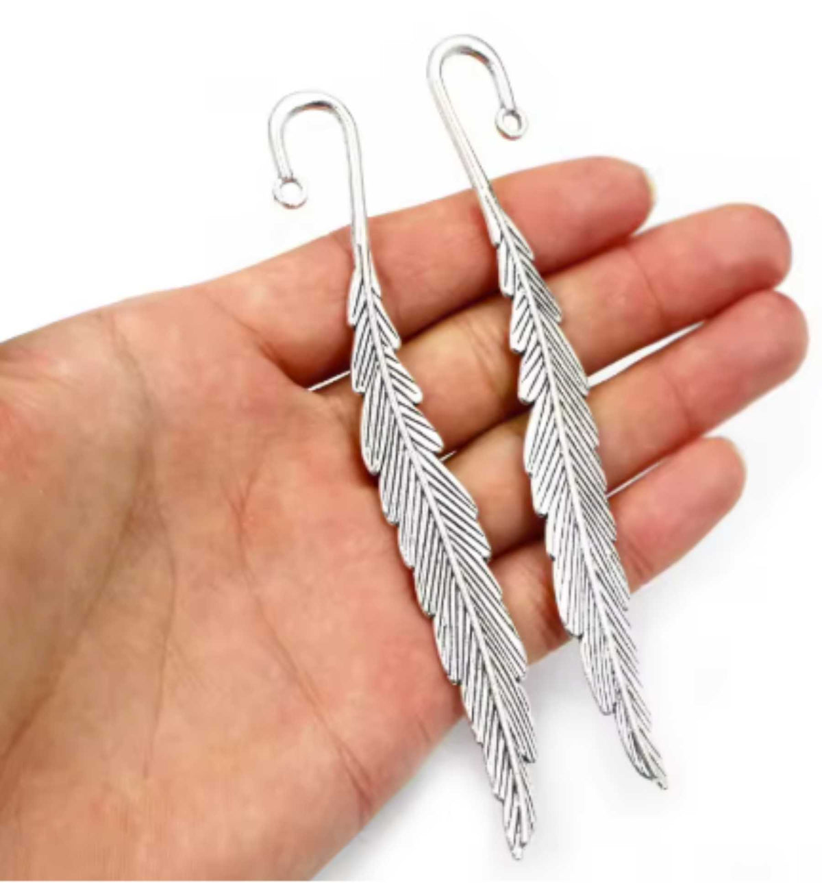 Silver-tone 13 x 116mm metal feather bookmark held in a hand