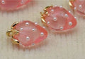 Close-up of 13 x 19mm translucent pink acrylic strawberry charms dotted with tiny pearls, with gold-tone leaf caps