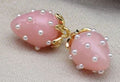 Close-up of 13 x 19mm pink acrylic strawberry charms dotted with tiny pearls, with gold-tone leaf caps