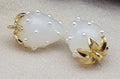 Close-up of 13 x 19mm white acrylic strawberry charms dotted with tiny pearls, with gold-tone leaf caps