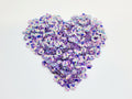 Heart-shaped pile of 6mm iridescent flower sequins in purple