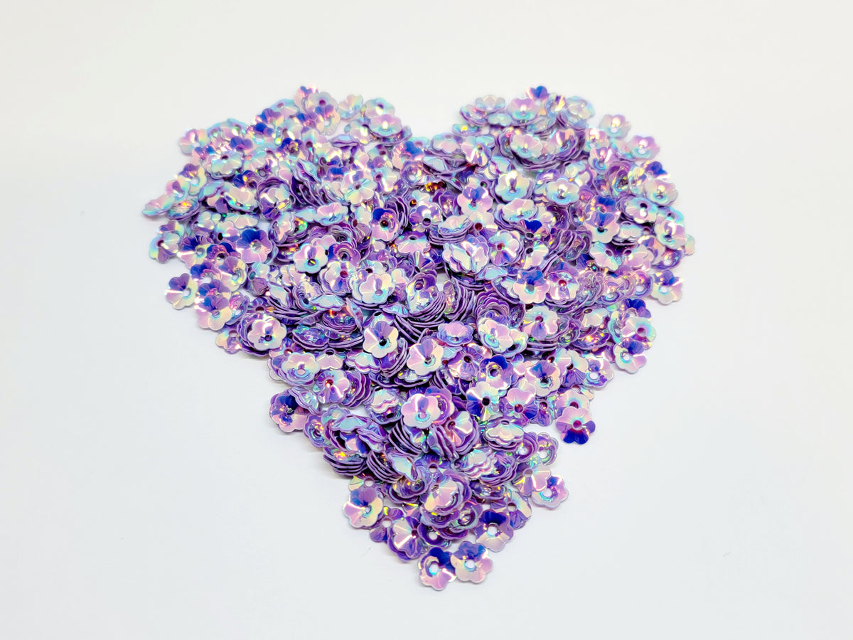 Heart-shaped pile of 6mm iridescent flower sequins in purple