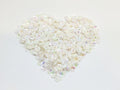 Heart-shaped pile of 6mm iridescent flower sequins in ivory on a white background