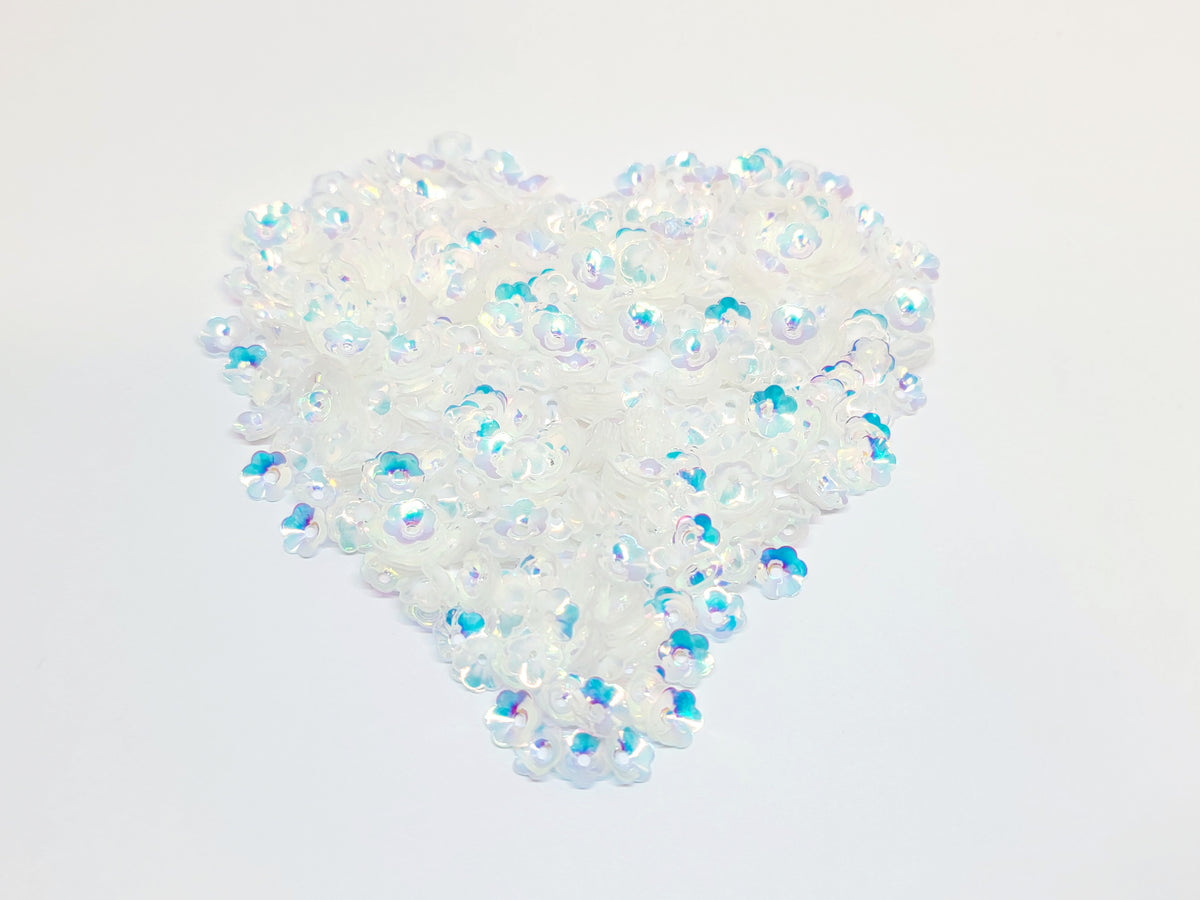 Heart-shaped pile of 6mm iridescent flower sequins in crystal white