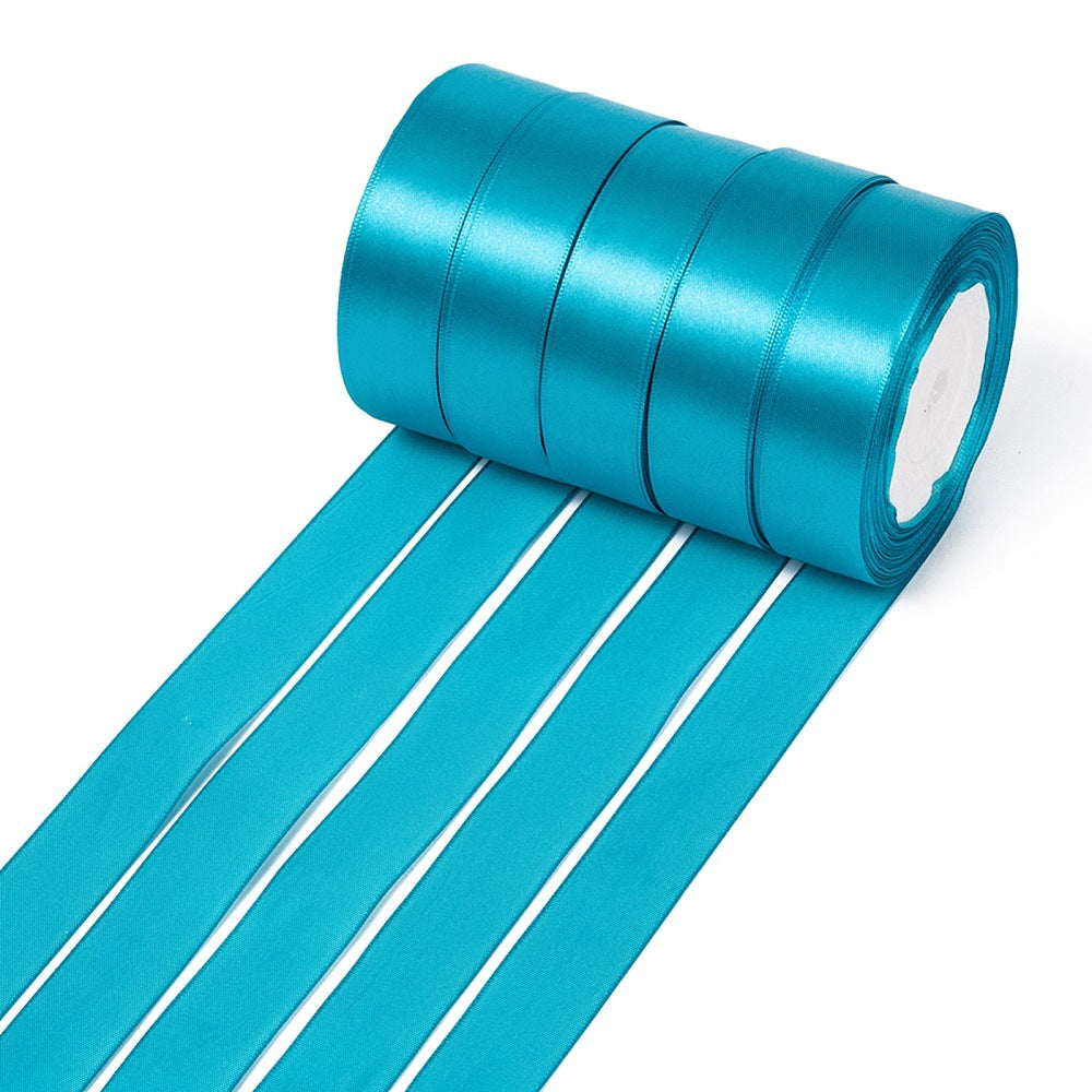 Rolls of 1-inch teal single-faced satin ribbon with a loose length