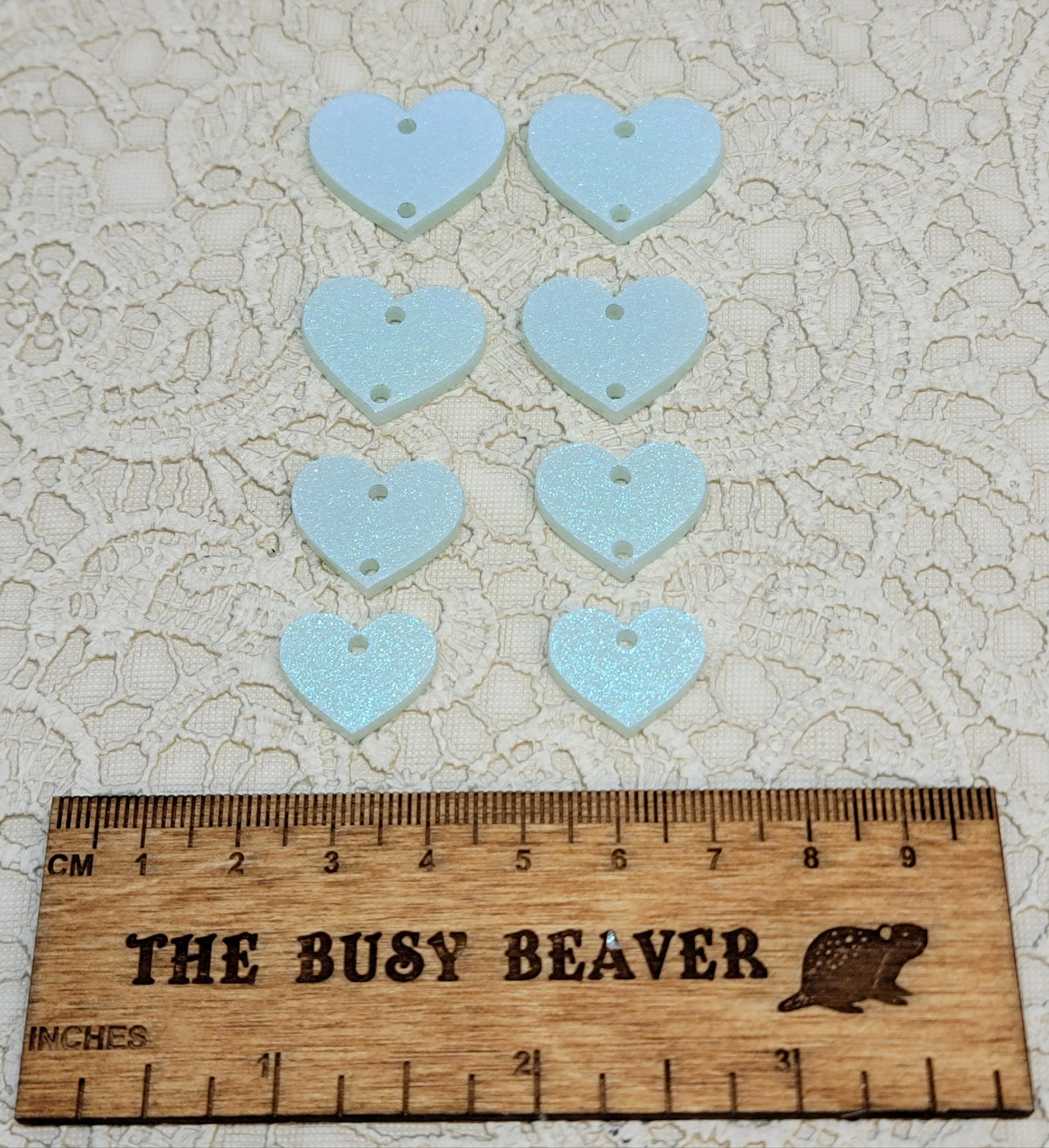 Two sets of four graduated acrylic hearts in iridescent icy blue, beside a ruler