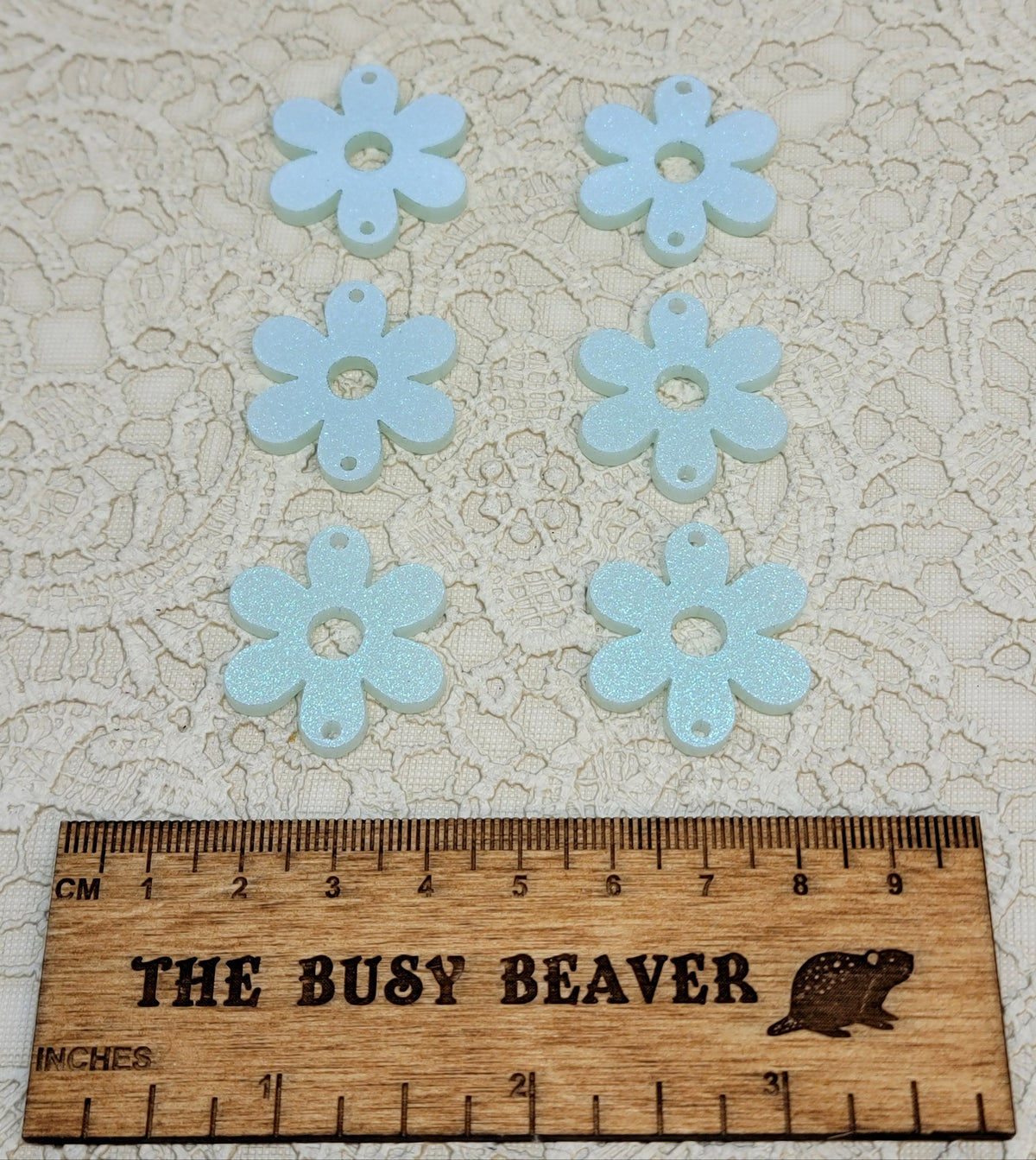 Two sets of three graduated acrylic flower pieces in iridescent icy blue, beside a ruler