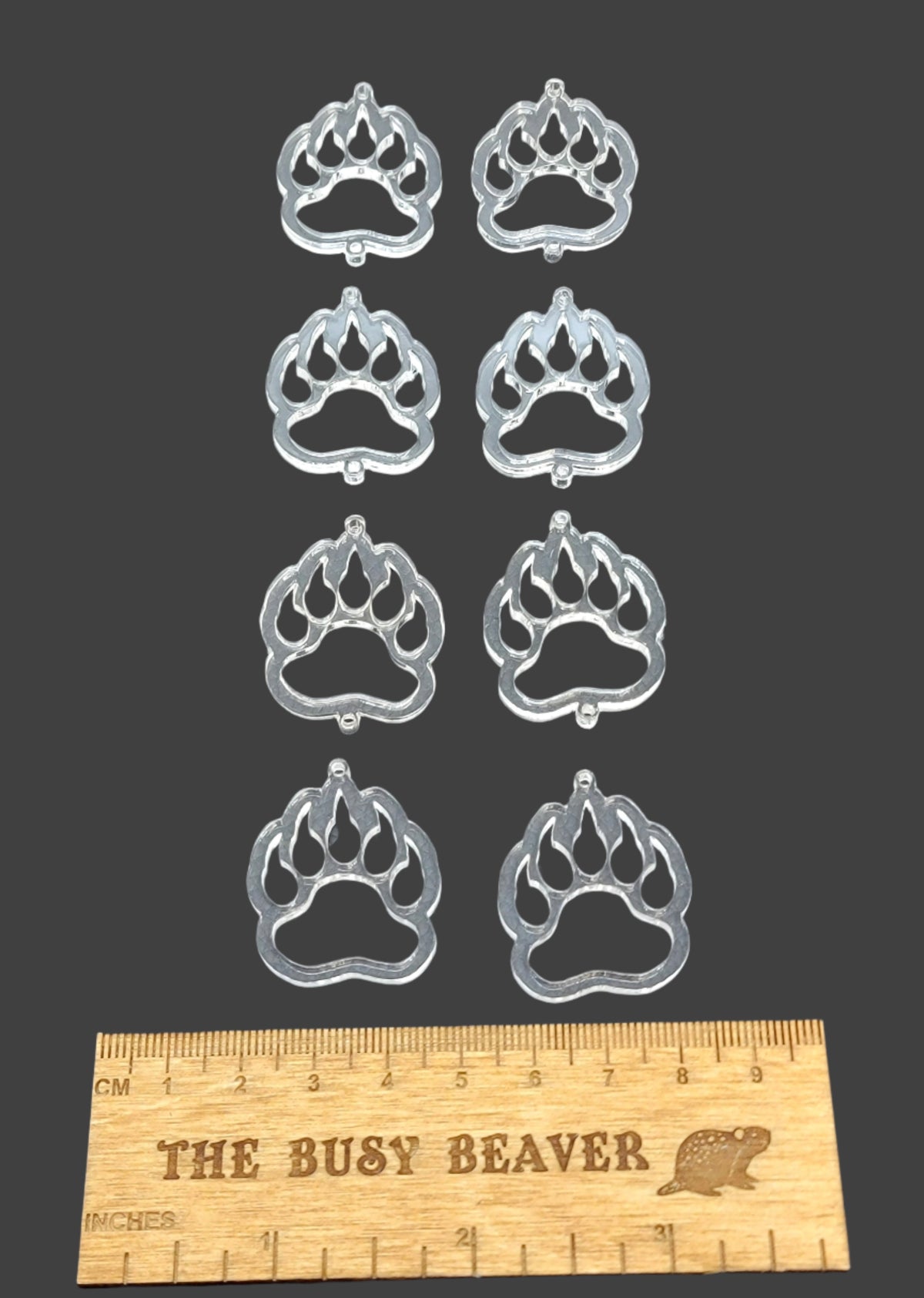 Two sets of four graduated acrylic open bear paws in clear, beside a ruler