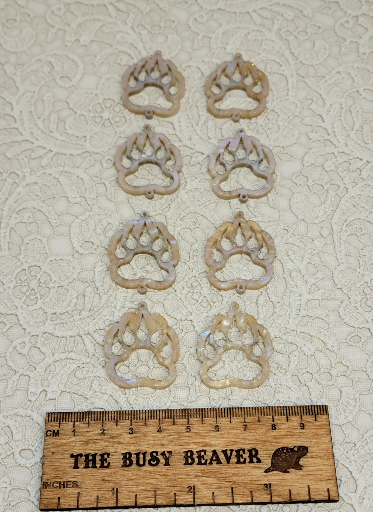Two sets of four graduated acrylic open bear paws in apricot ripple with glitter, beside a ruler
