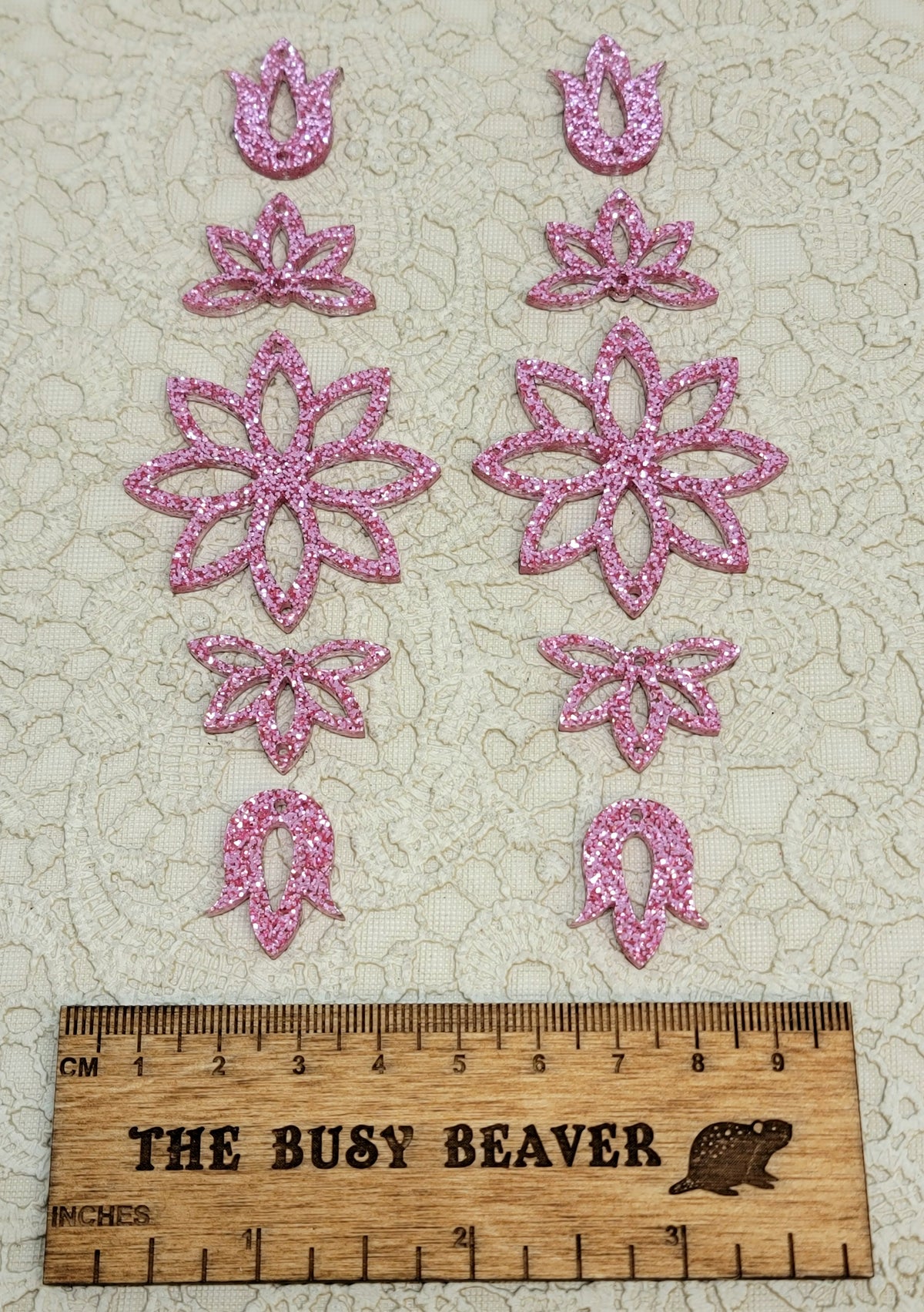 Two 5-tier acrylic flower earring sets in pink glitter, laid out top to bottom beside a ruler