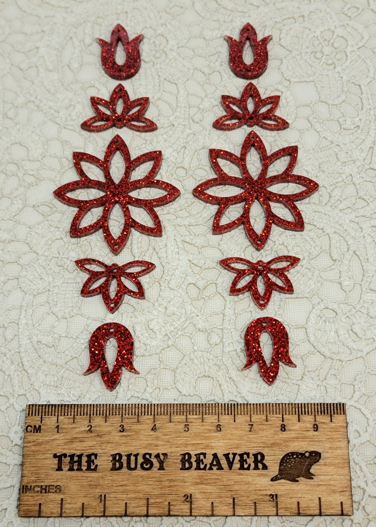 Two 5-tier acrylic flower earring sets in red glitter, laid out top to bottom beside a ruler