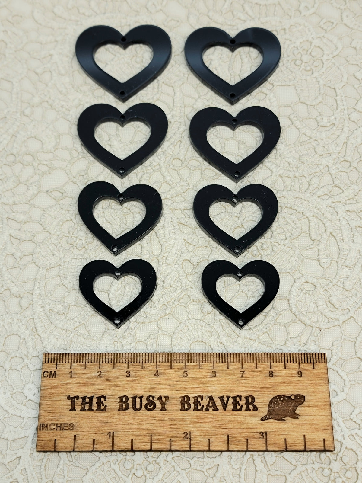 Two sets of four graduated acrylic open hearts in black, beside a ruler