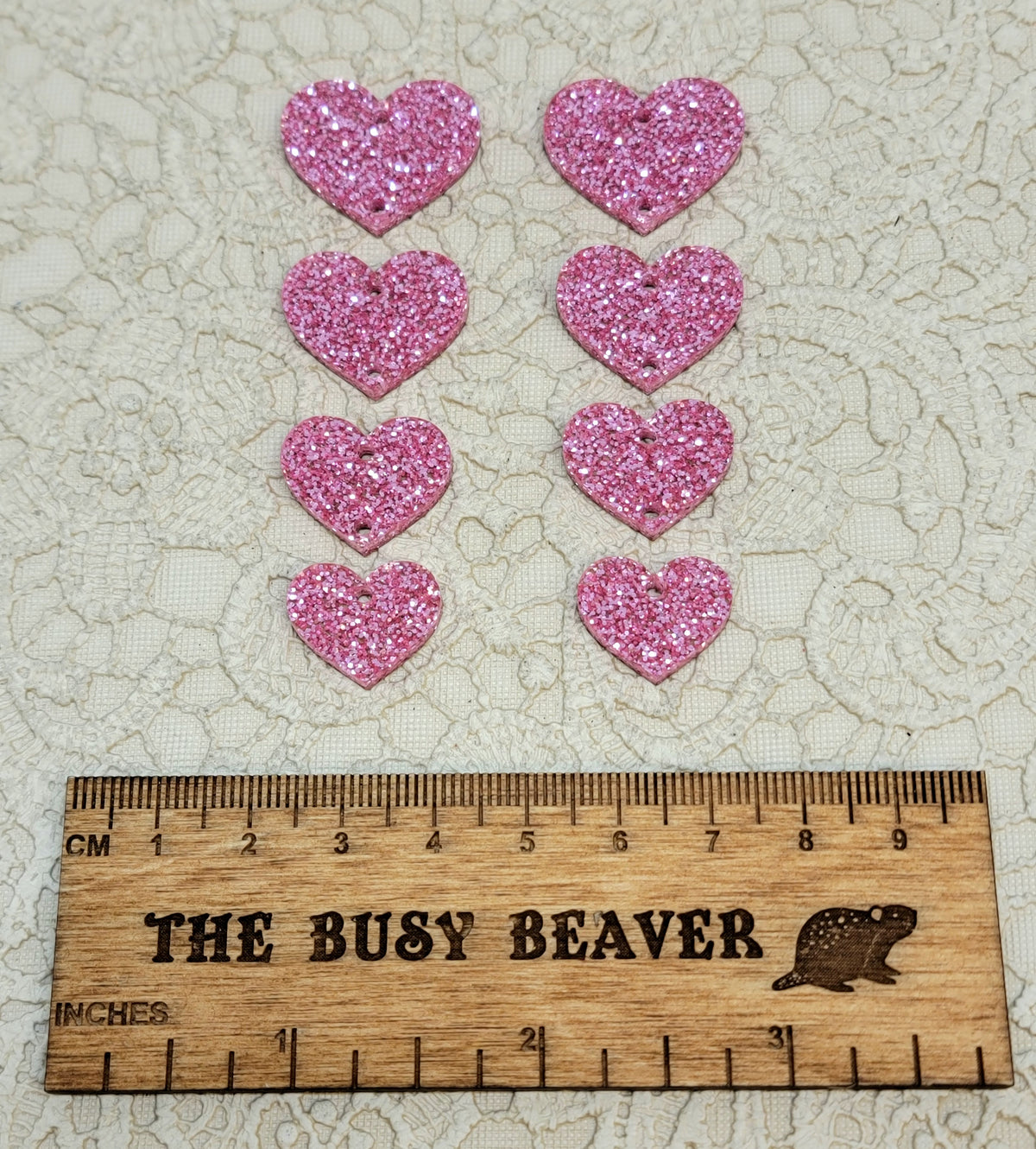 Two sets of four graduated acrylic hearts in pink glitter, beside a ruler