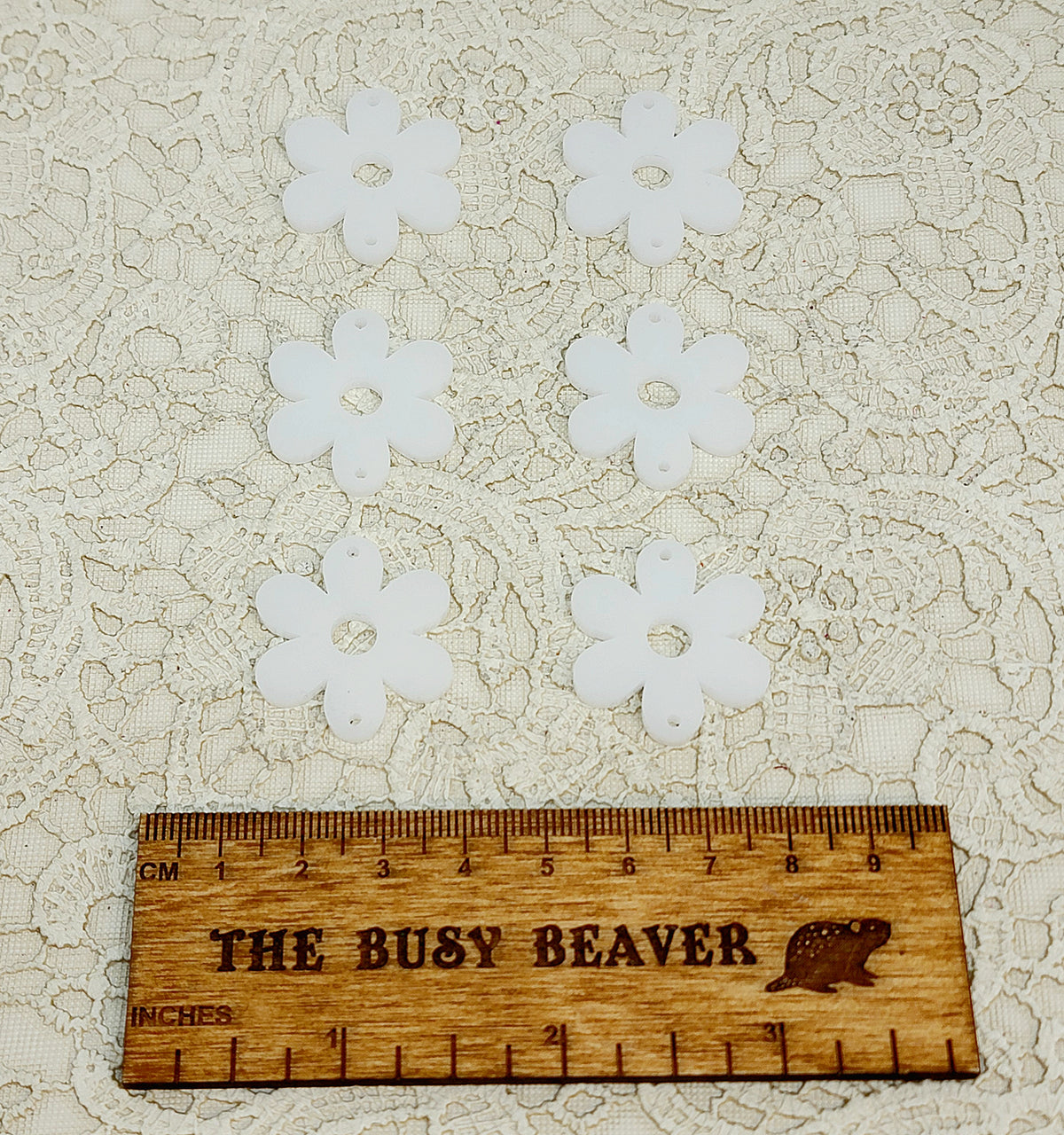 Two sets of three graduated acrylic flower pieces in linen, beside a ruler