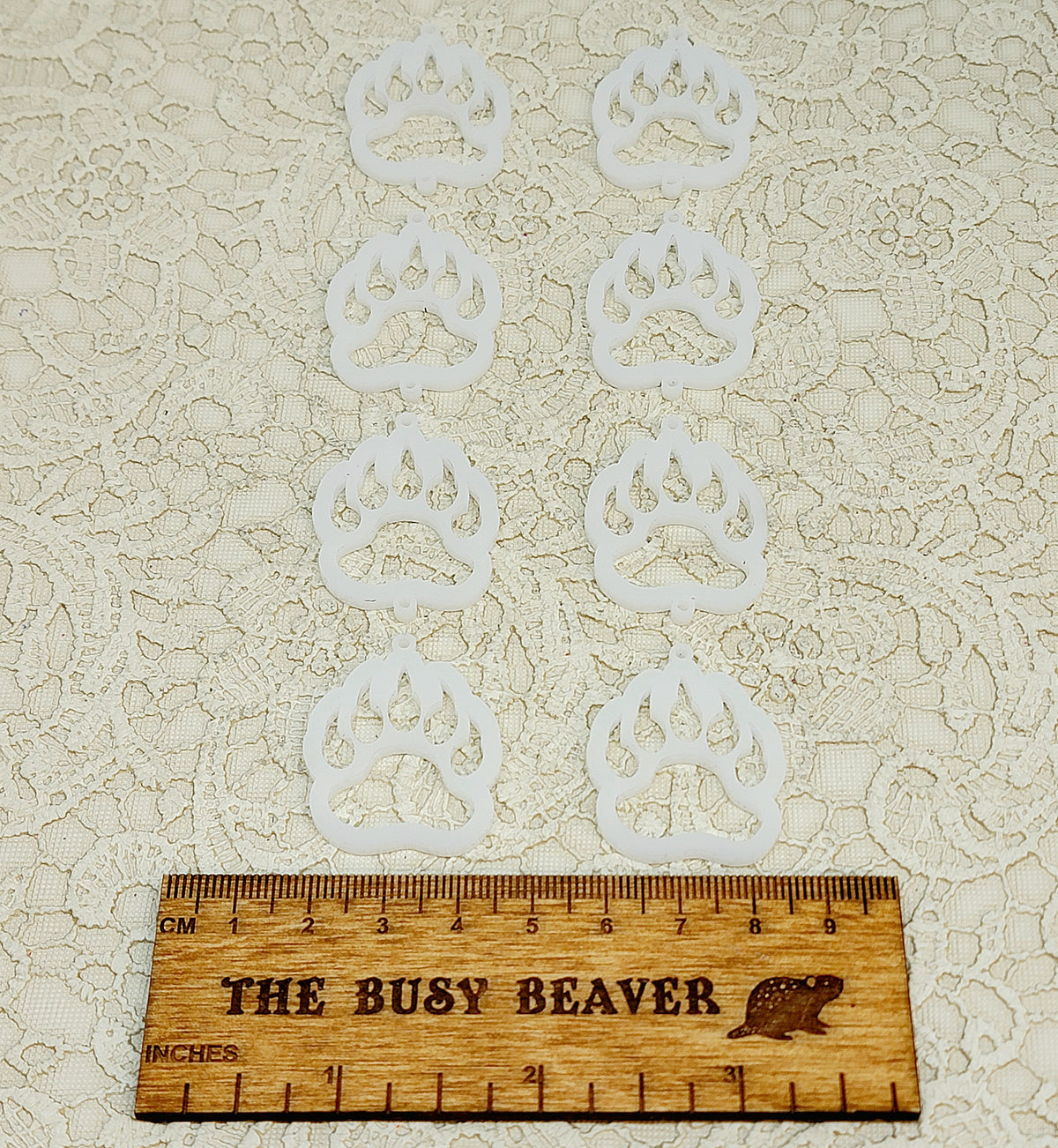 Two sets of four graduated acrylic open bear paws in frosty white, beside a ruler