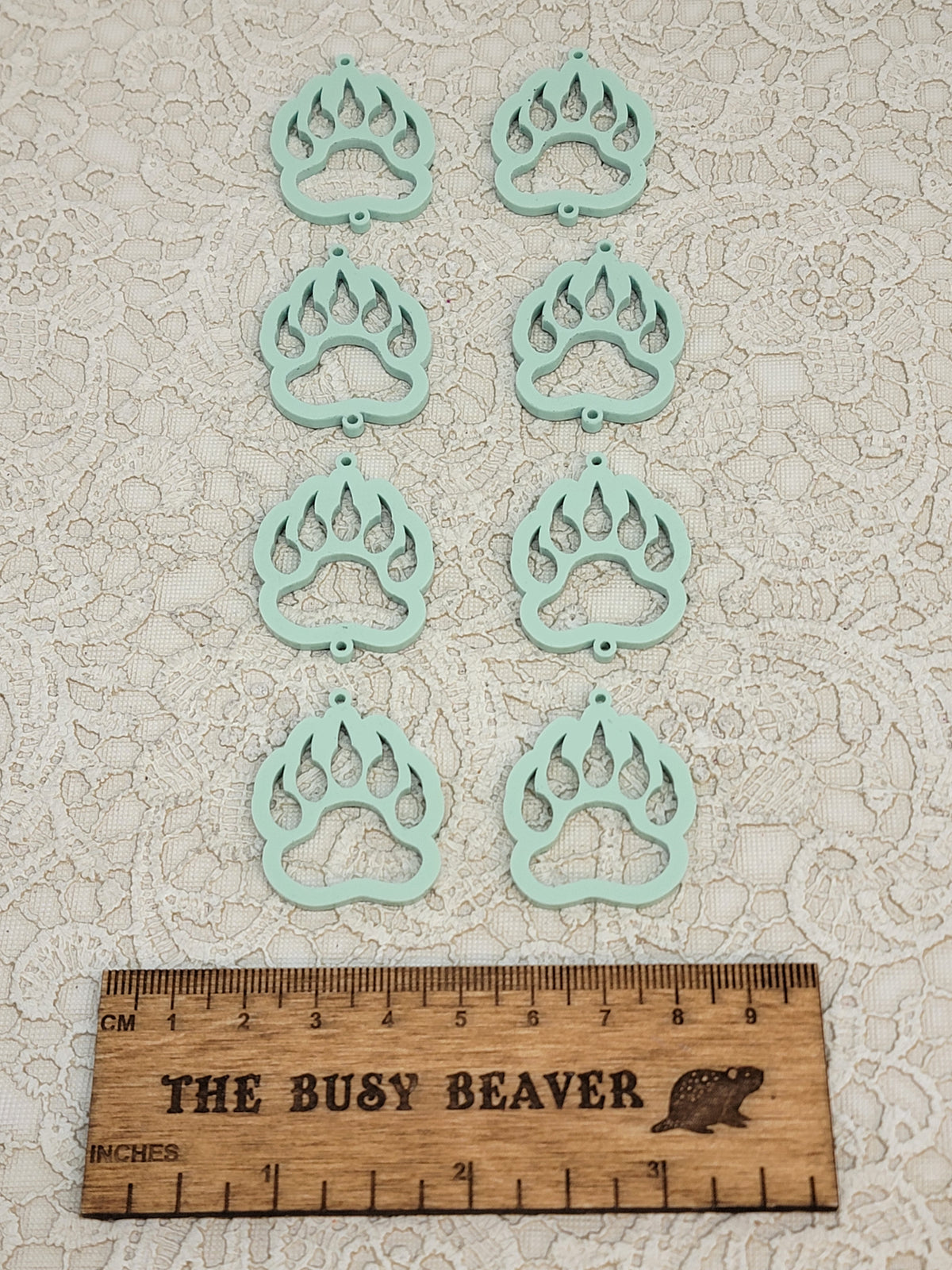 Two sets of four graduated acrylic open bear paws in pastel sage, beside a ruler