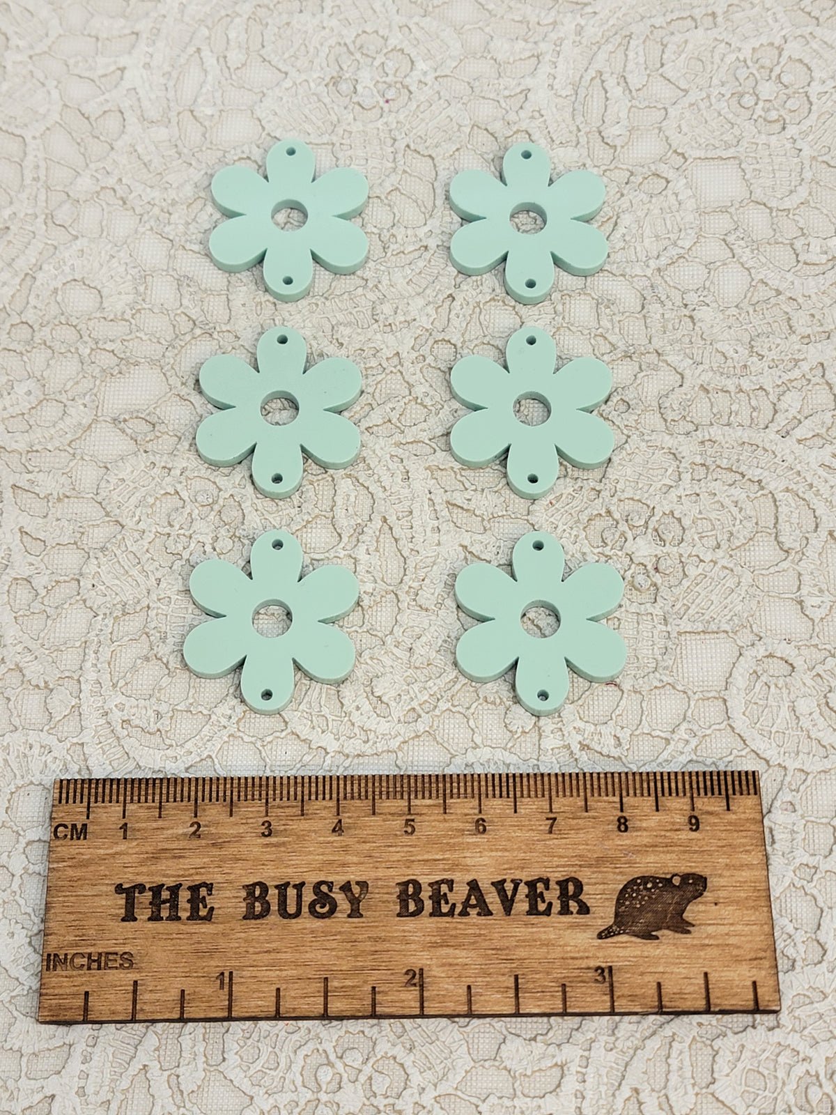 Two sets of three graduated acrylic flower pieces in pastel sage, beside a ruler