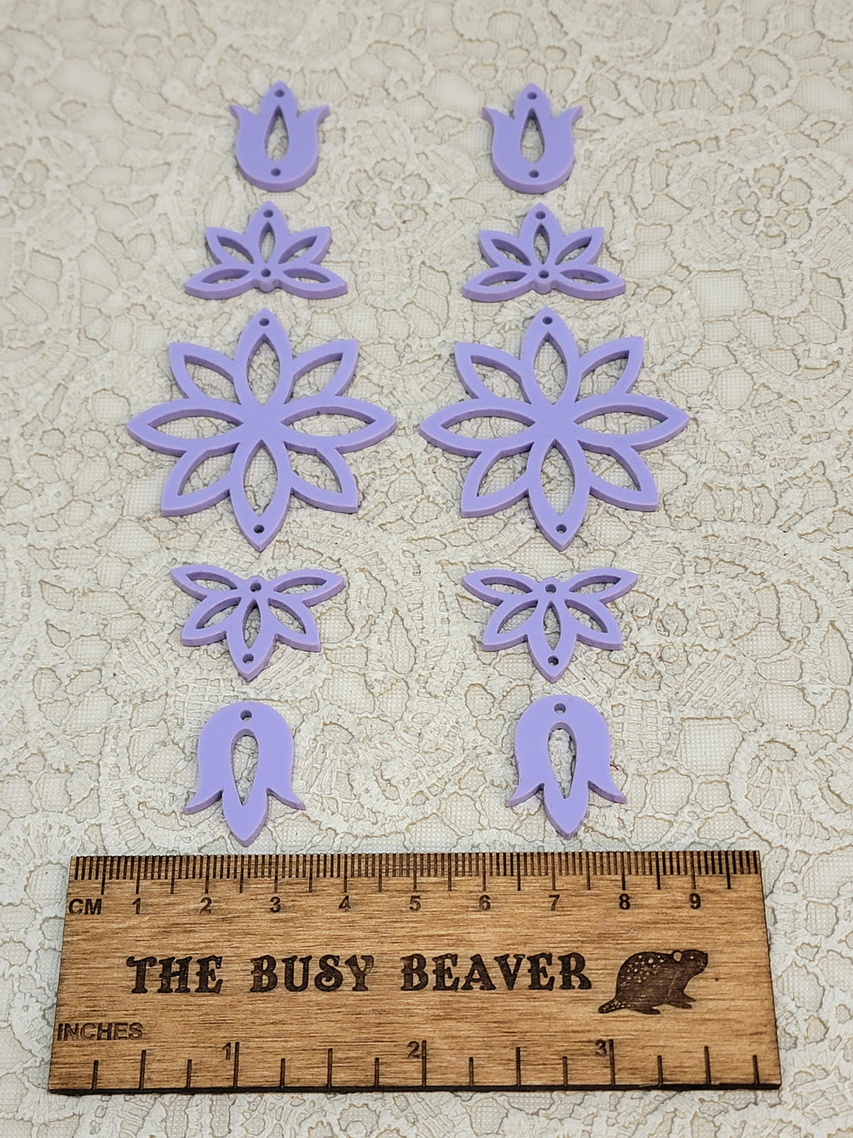 Two 5-tier acrylic flower earring sets in pastel purple, laid out top to bottom beside a ruler