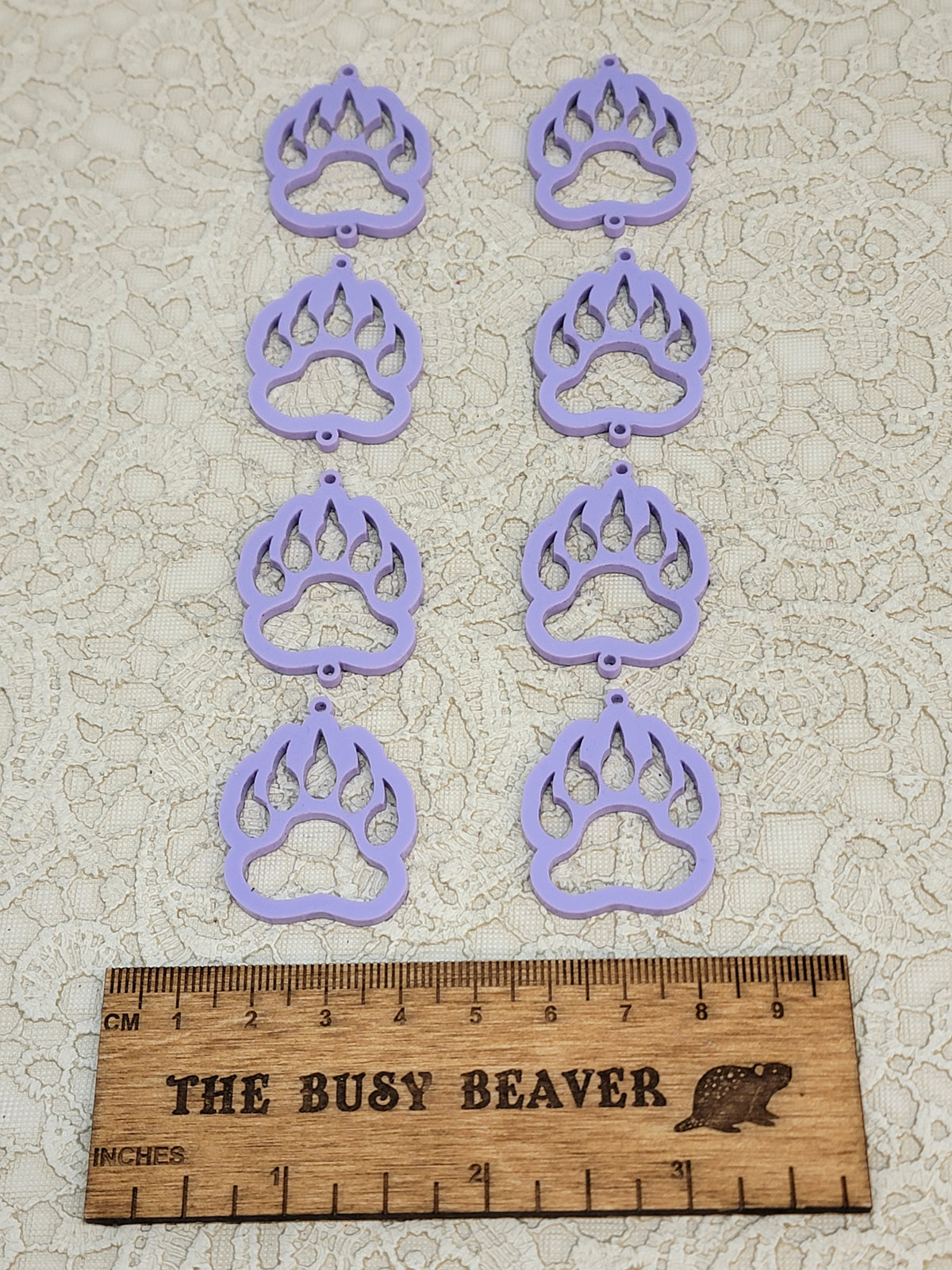Two sets of four graduated acrylic open bear paws in pastel purple, beside a ruler