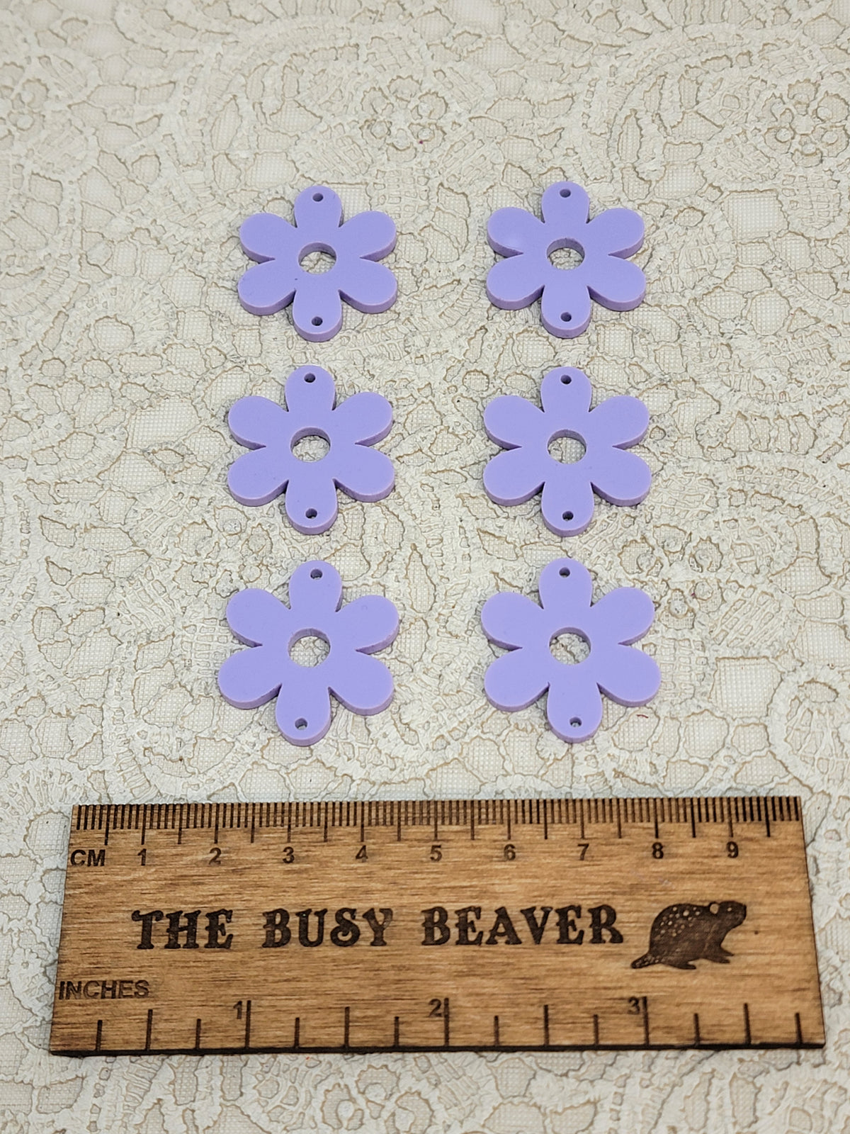 Two sets of three graduated acrylic flower pieces in pastel purple, beside a ruler