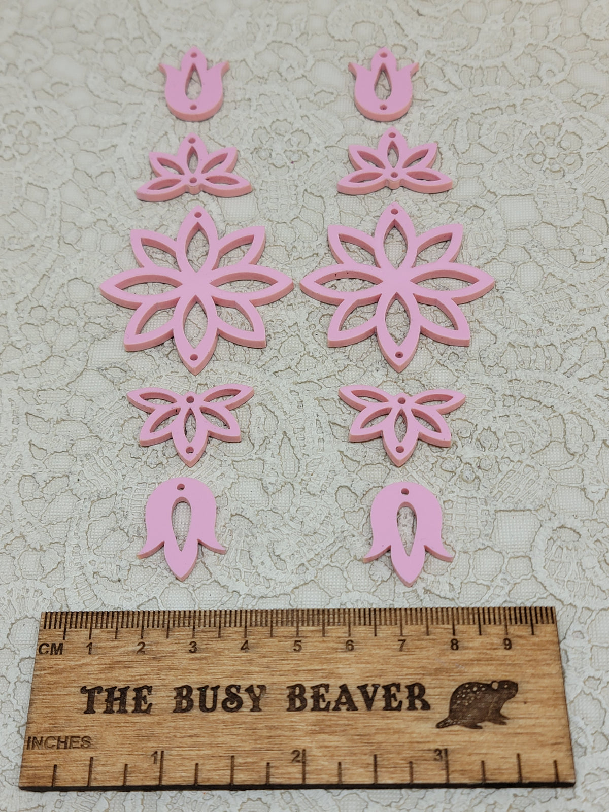 Two 5-tier acrylic flower earring sets in pastel pink, laid out top to bottom beside a ruler