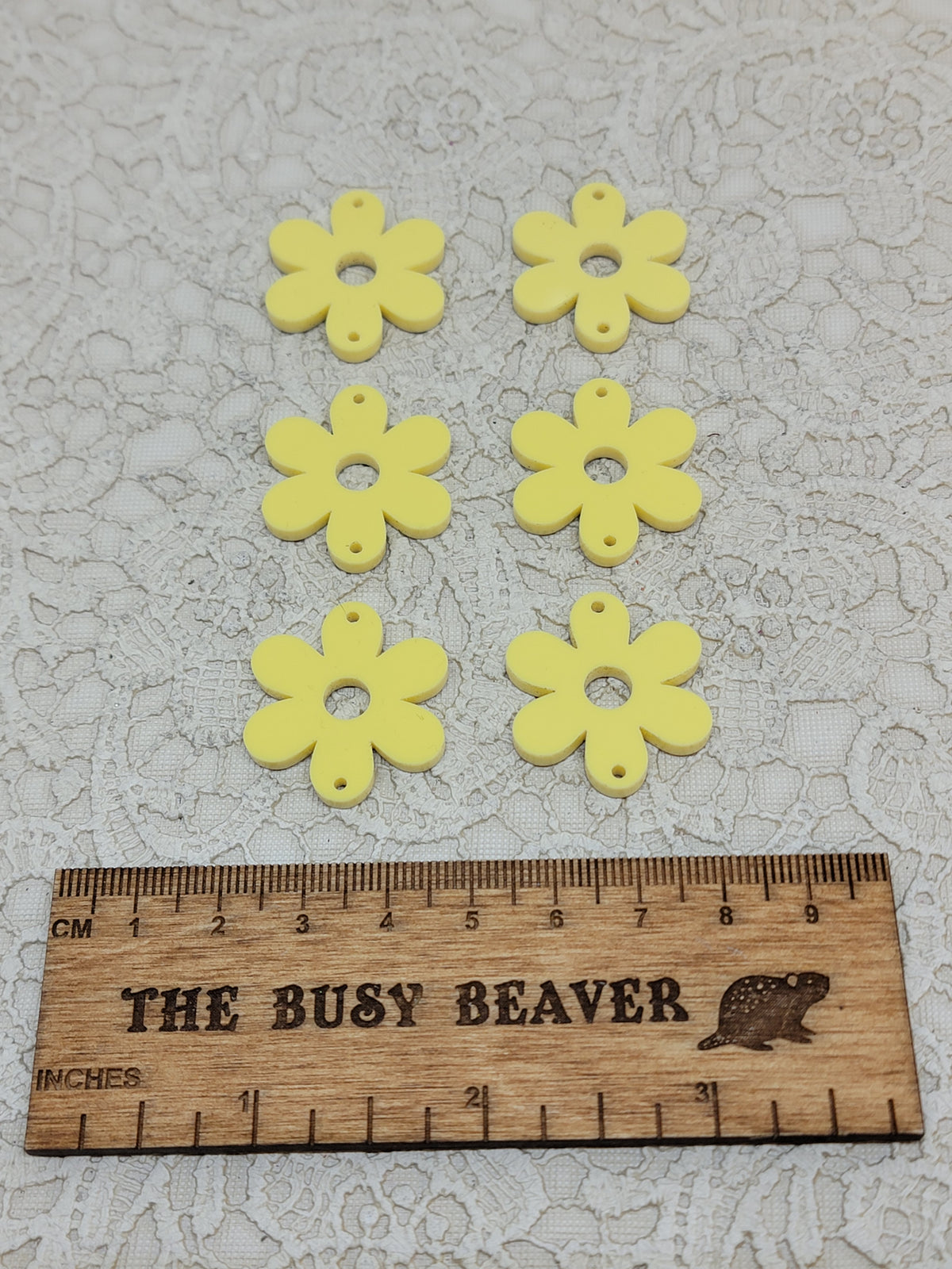 Two sets of three graduated acrylic flower pieces in pastel yellow, beside a ruler