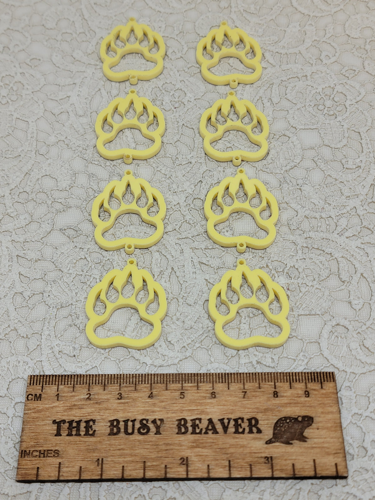 Two sets of four graduated acrylic open bear paws in pastel yellow, beside a ruler