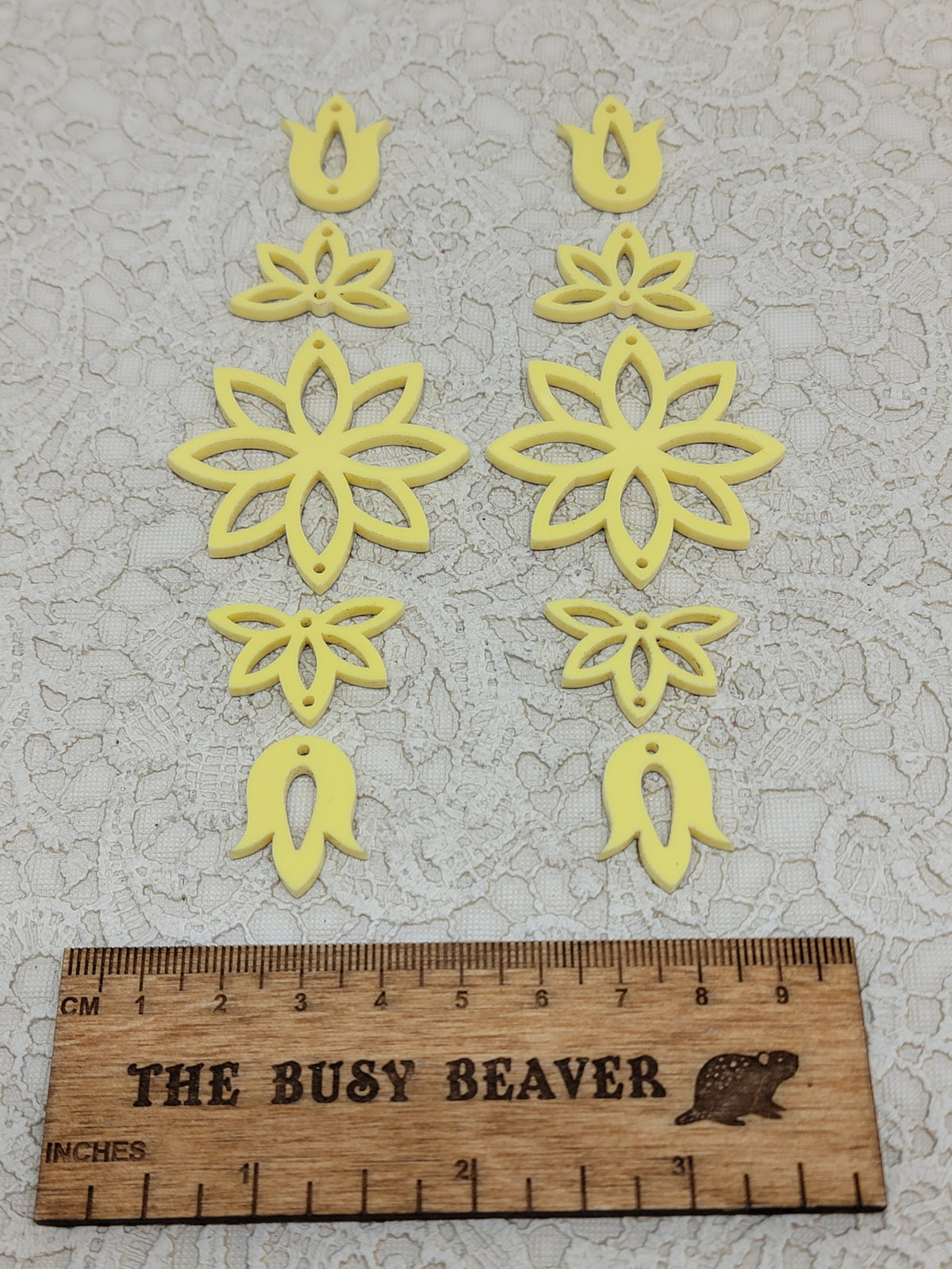 Two 5-tier acrylic flower earring sets in pastel yellow, laid out top to bottom beside a ruler