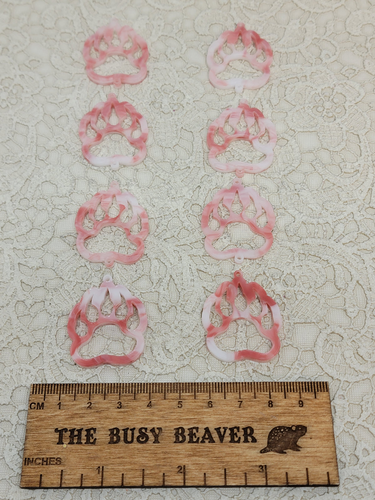 Two sets of four graduated acrylic open bear paws in red/white marble, beside a ruler