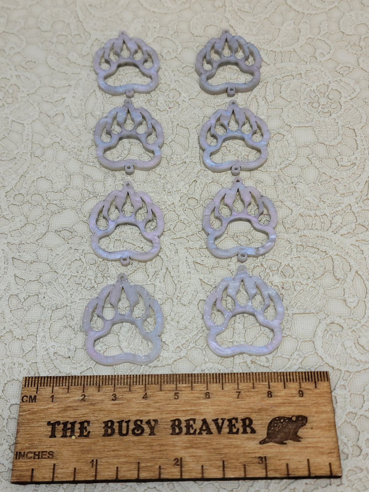 Two sets of four graduated acrylic open bear paws in icy marble, beside a ruler