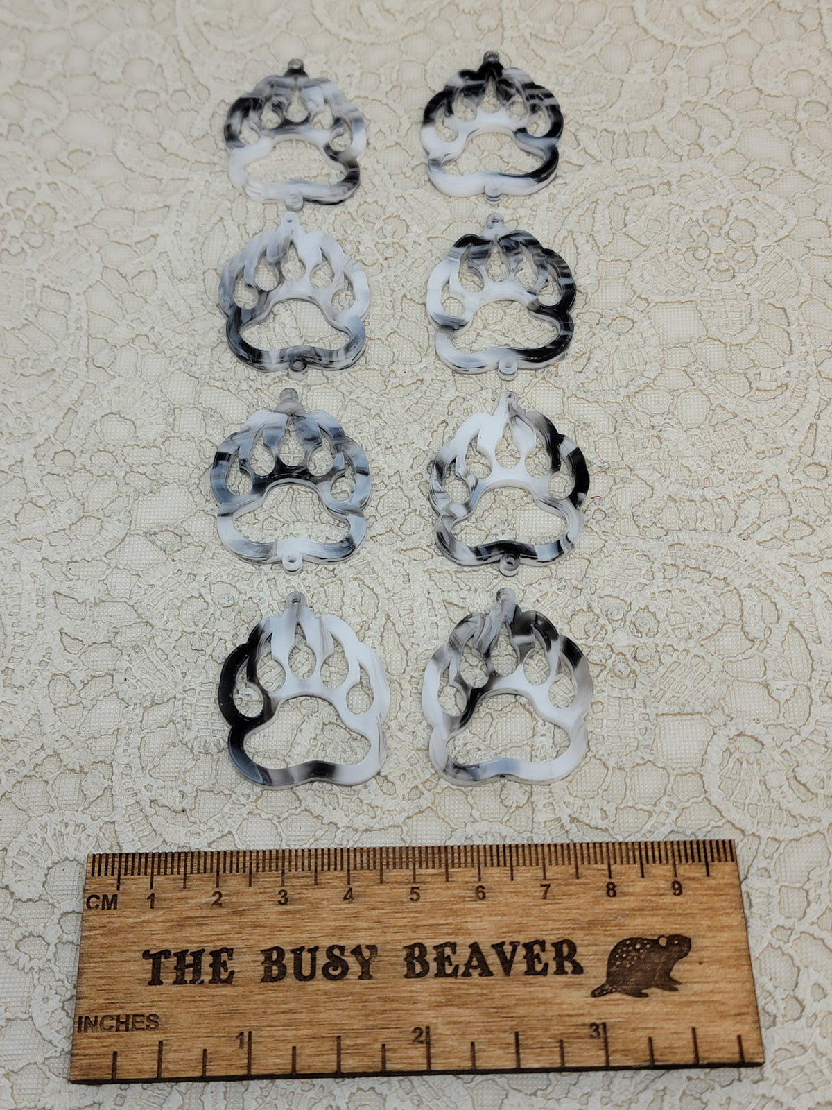Two sets of four graduated acrylic open bear paws in black/white marble, beside a ruler