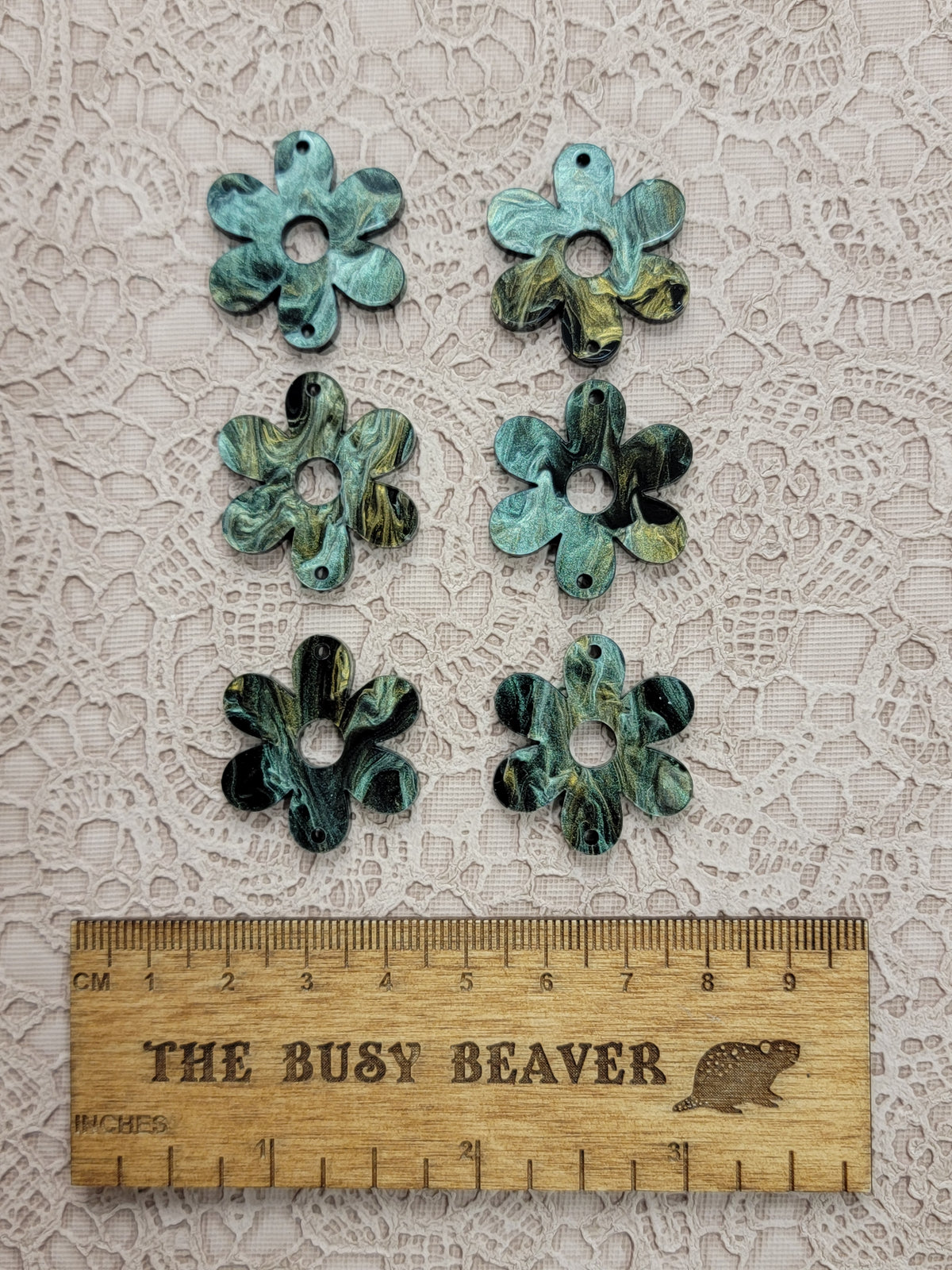Two sets of three graduated acrylic flower pieces in gold/green/black marble, beside a ruler