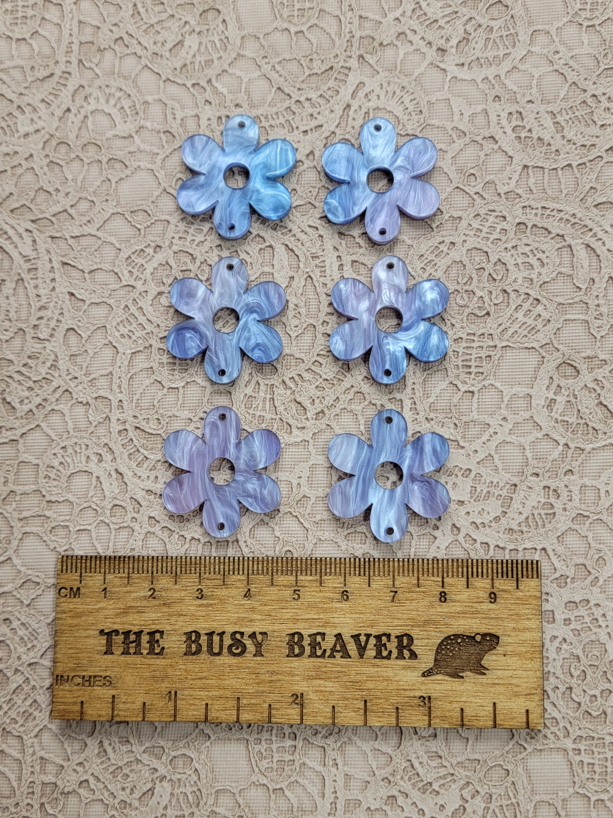 Two sets of three graduated acrylic flower pieces in fuchsia/blue marble, beside a ruler