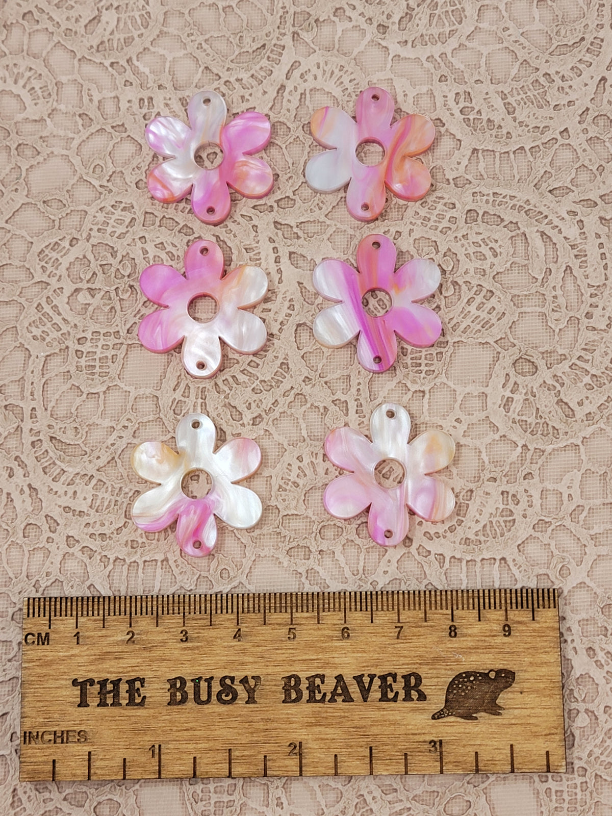 Two sets of three graduated acrylic flower pieces in pink/orange marble, beside a ruler