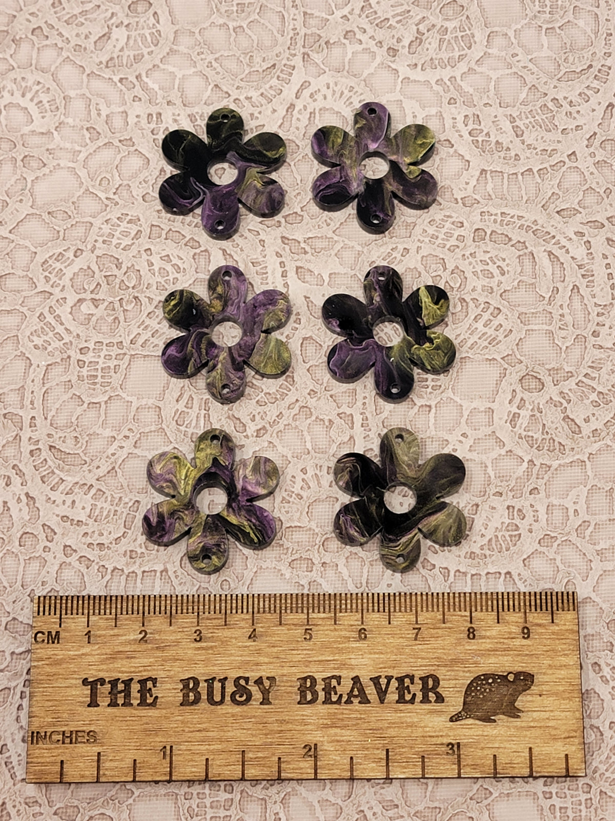 Two sets of three graduated acrylic flower pieces in purple/gold/black marble, beside a ruler
