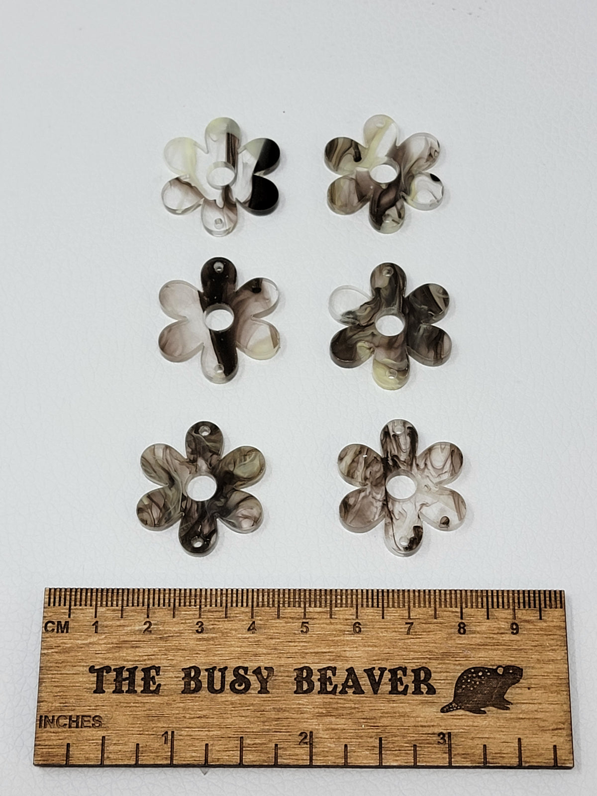 Two sets of three graduated acrylic flower pieces in brown/cream marble, beside a ruler
