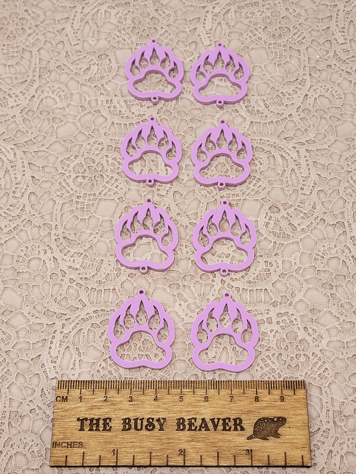 Two sets of four graduated acrylic open bear paws in dark pink pastel, beside a ruler