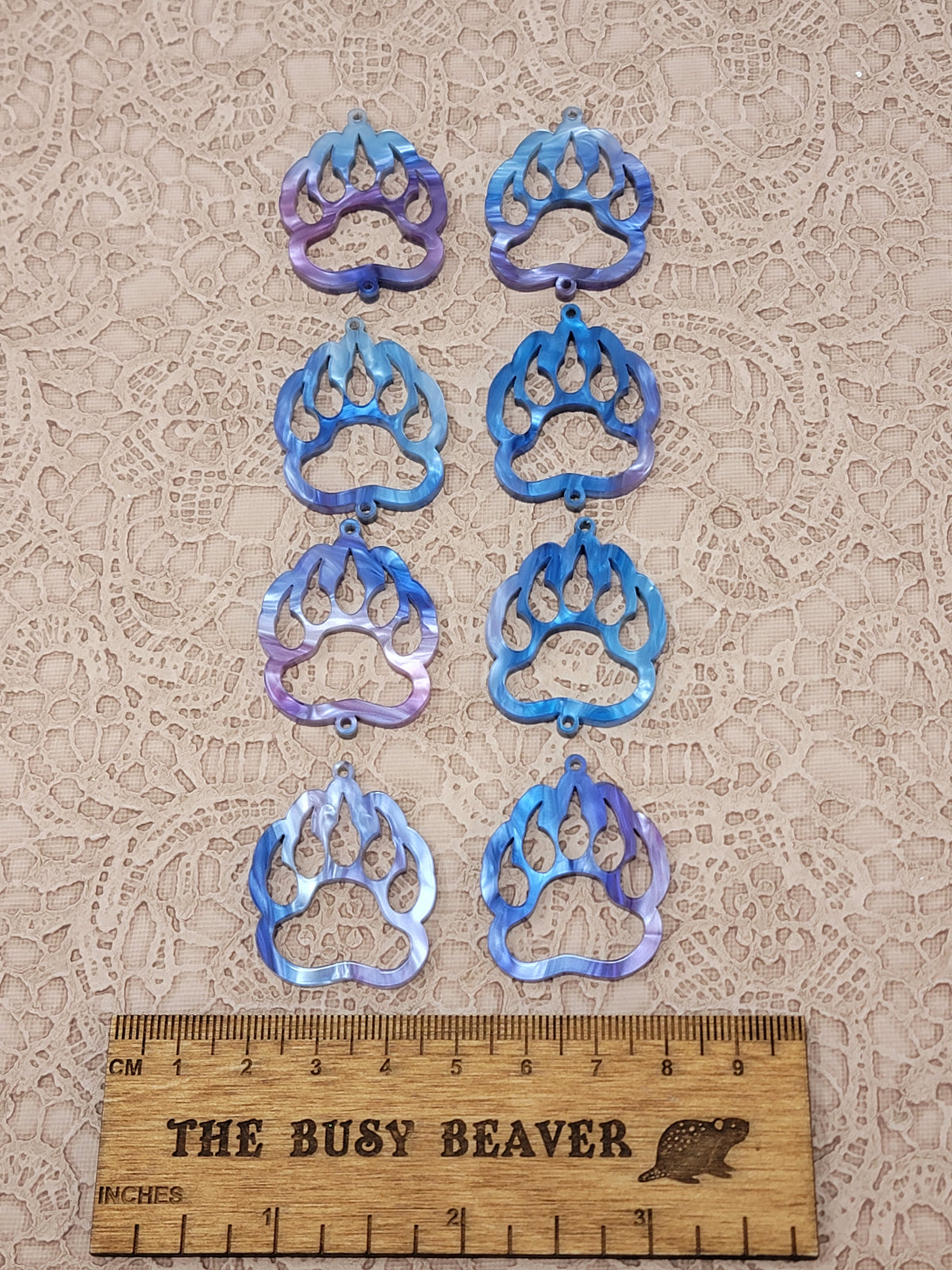 Two sets of four graduated acrylic open bear paws in fuchsia/blue marble, beside a ruler